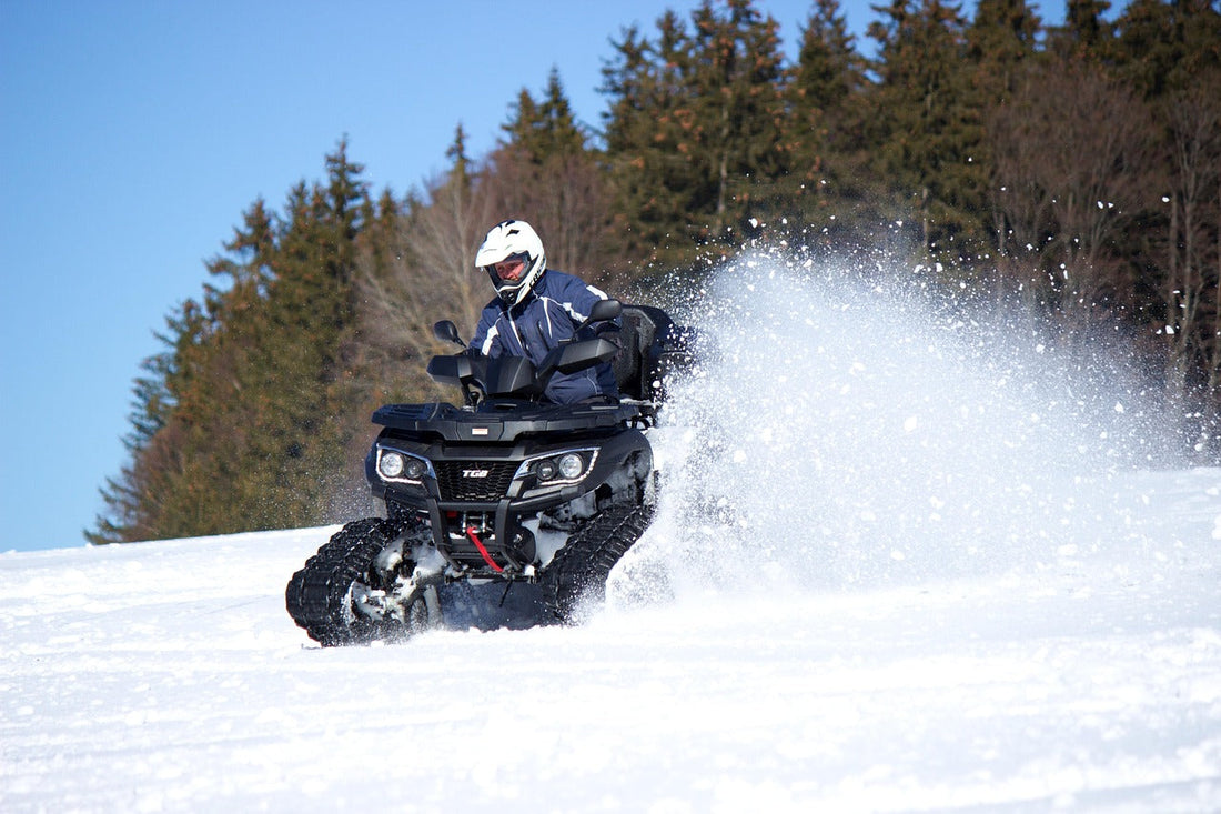 ATV riding in winter snow with a rider using heated gear on a snow-covered trail